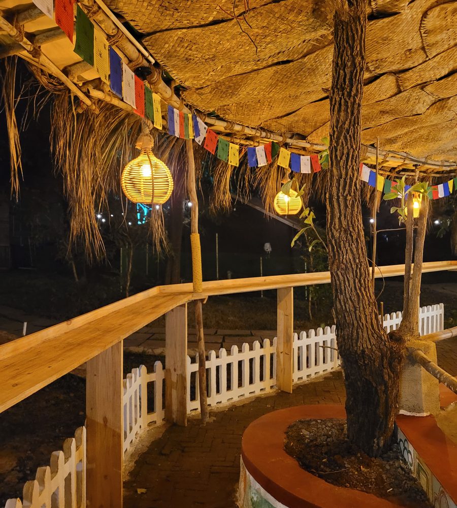 the café at night, prayer flags and hanging lanterns under the thatch