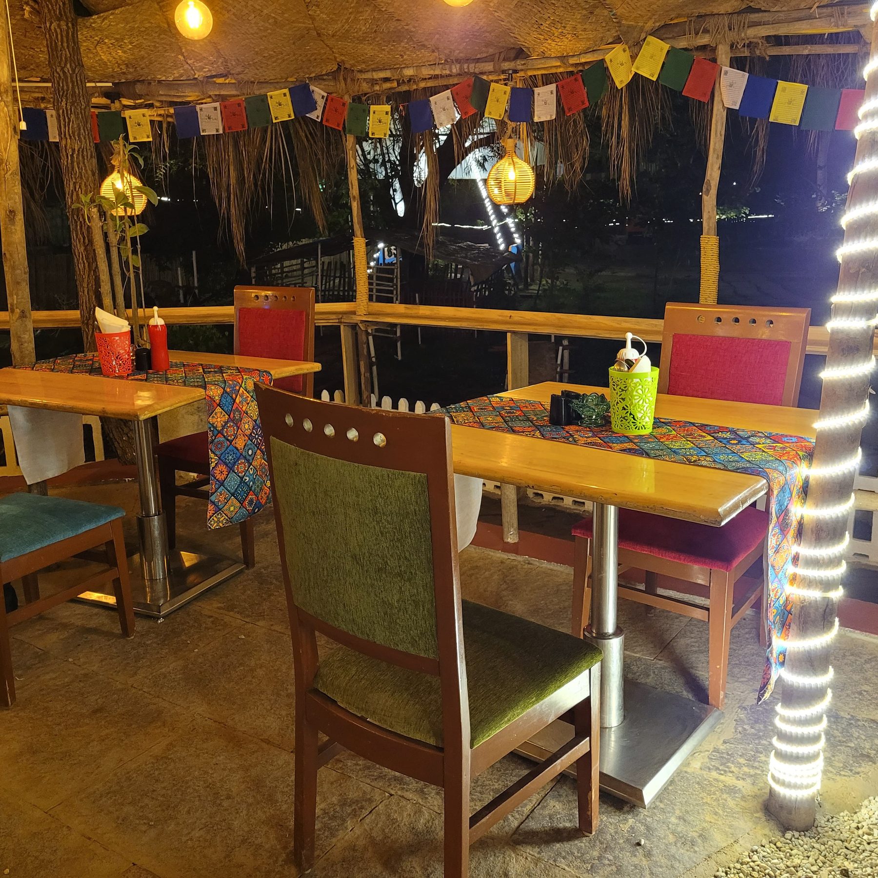 the café at night, bulb strings under the thatch