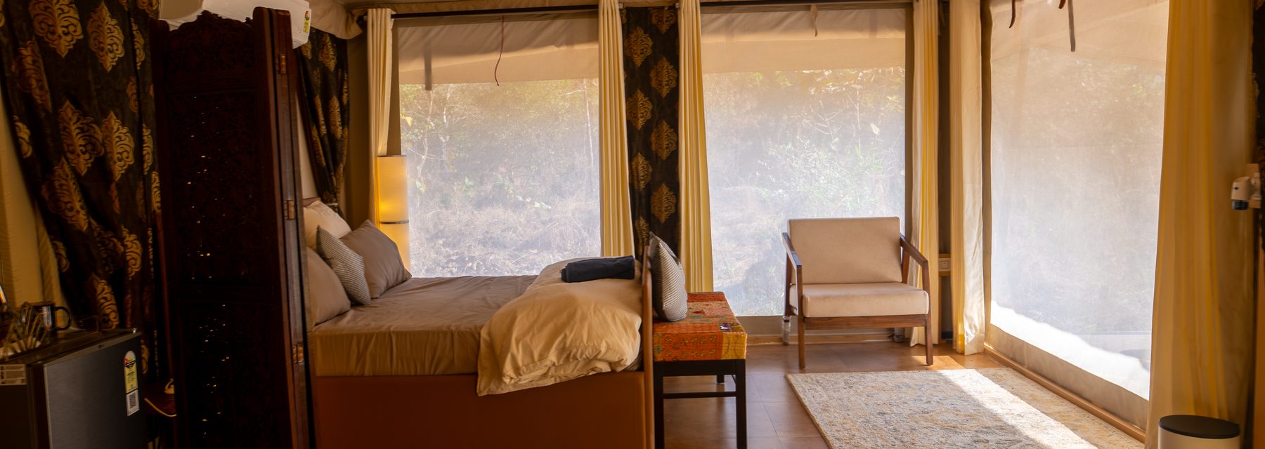 the bed seen from the doorway with the window seat and chair beyond