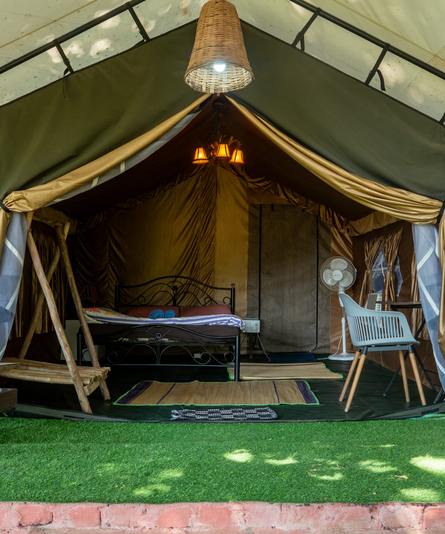 a glamping tent opened up, bed and lawn inside the canvas